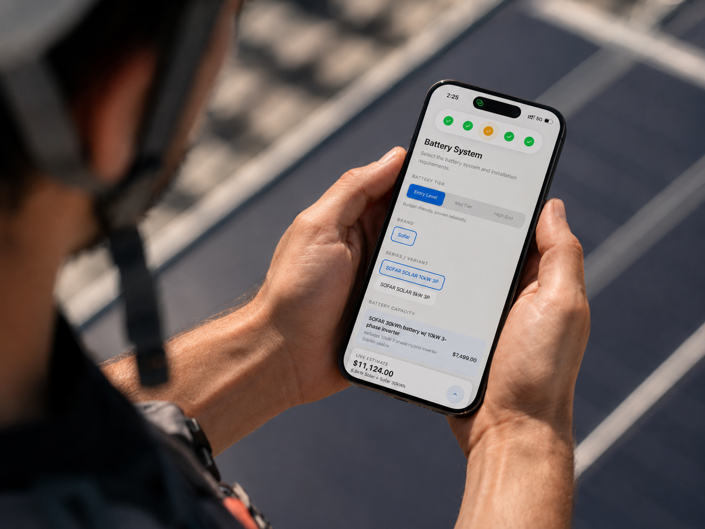 Sales rep building a battery estimate on a phone, standing over a solar array
